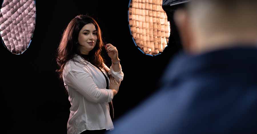 Mulher posando com confiança em estúdio de fotografia com iluminação profissional, durante ensaio fotográfico profissional com direção especializada.