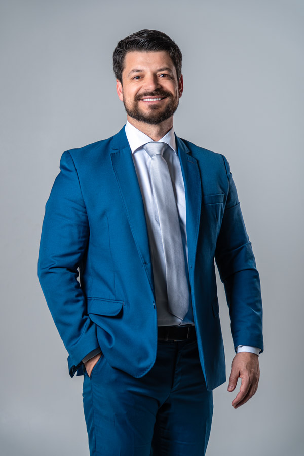 Homem com expressão séria e confiante encara a câmera diretamente, com fundo escuro. A imagem transmite firmeza e autoridade.