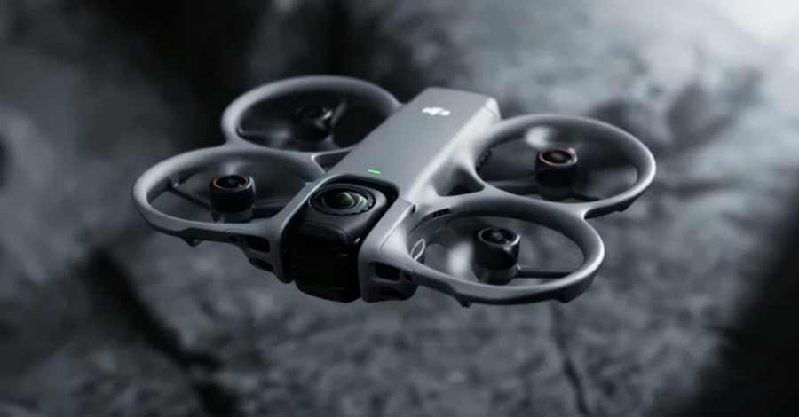 Drone compacto com hélices protegidas voando próximo ao chão, com câmera frontal em destaque.